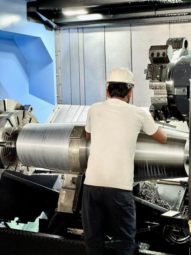 A heavy roll held in the chuck of a CNC lathe as the tool takes a cut.