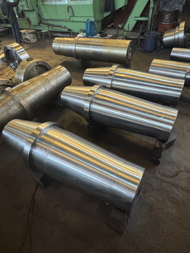 A crusher shaft standing on the floor beside the lathe.