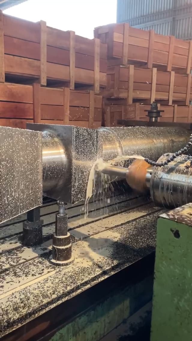 A shaft turning under the tool on the lathe, coolant running over the cut.