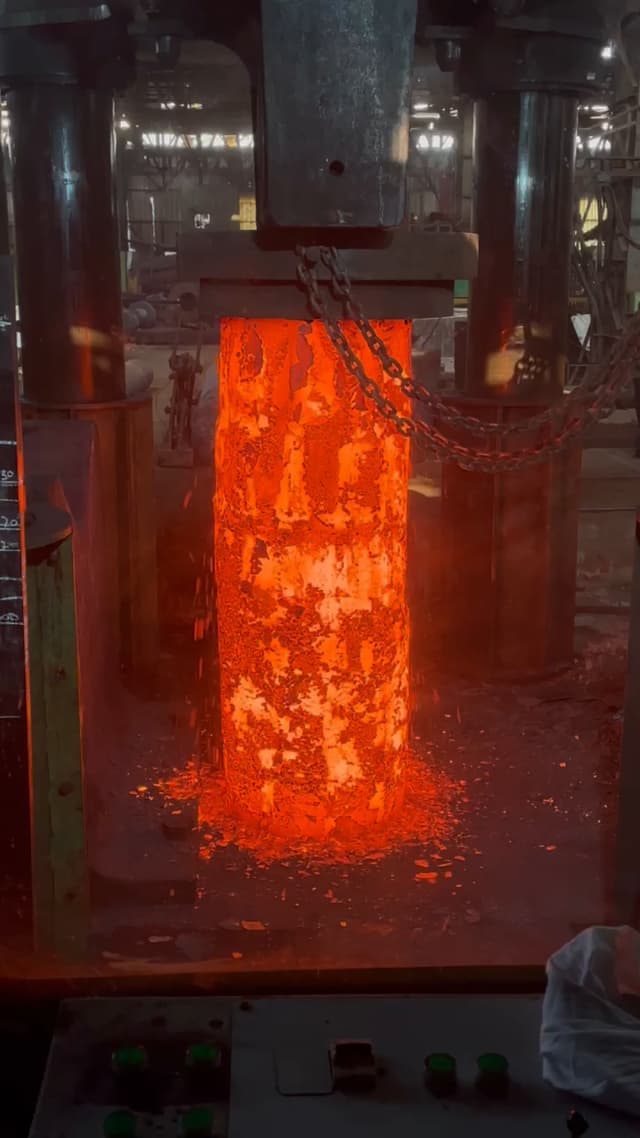 An ingot stood on end under the press, shortening and spreading as it is upset.